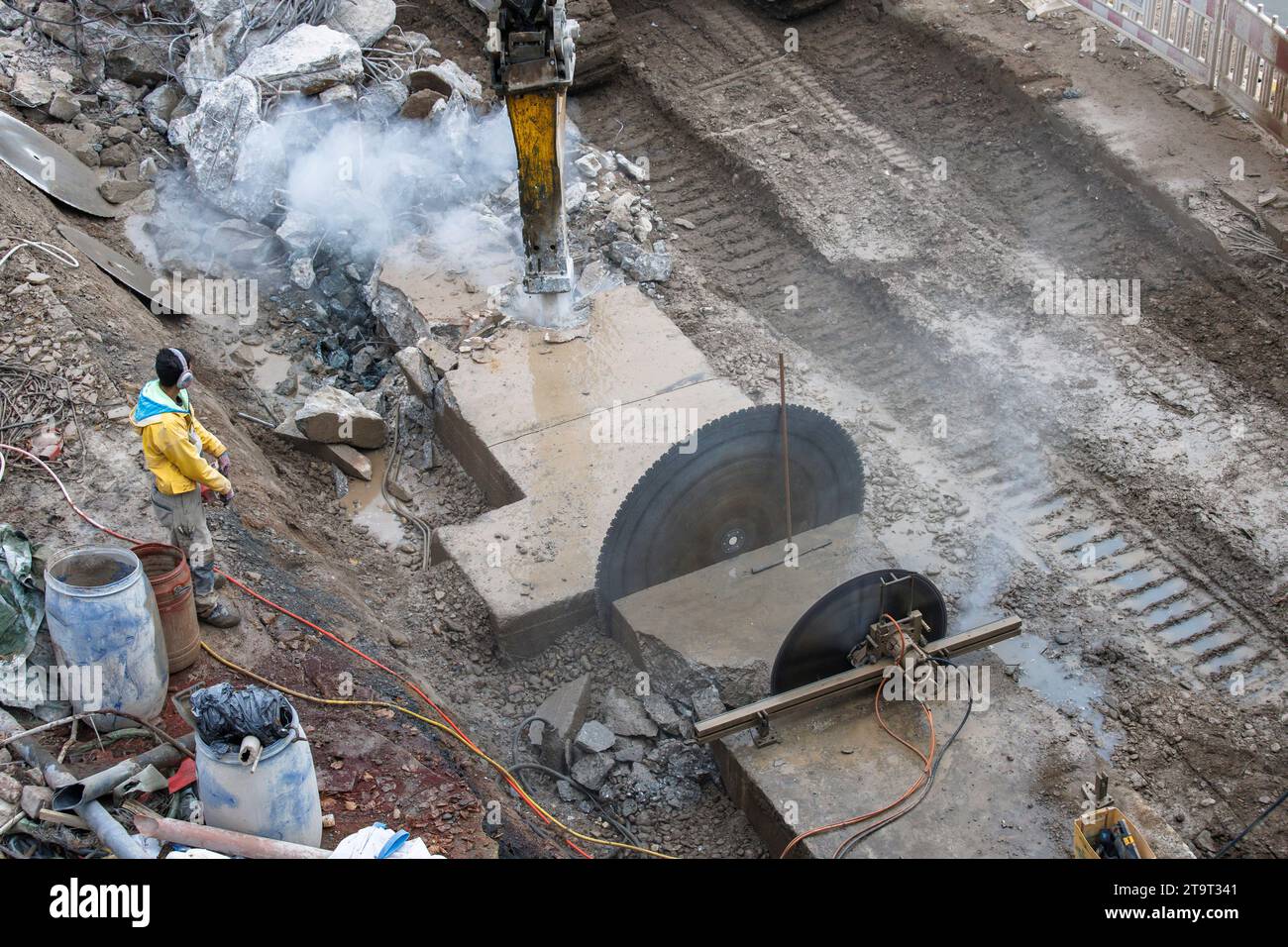 Demolizione di una base di cemento con una sega di cemento e un escavatore sulle rive del Reno, Colonia, Germania. Abriss eines Betonsockels mit Betonsae Foto Stock