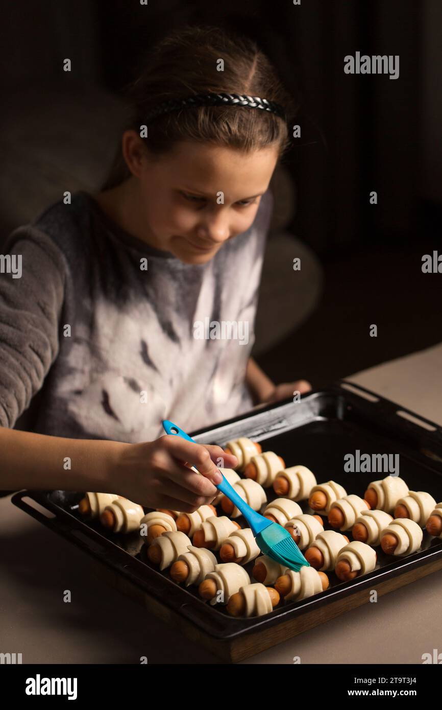 Una ragazza prepara un piatto di maiale in una coperta, spalma i panini con una spazzola Foto Stock