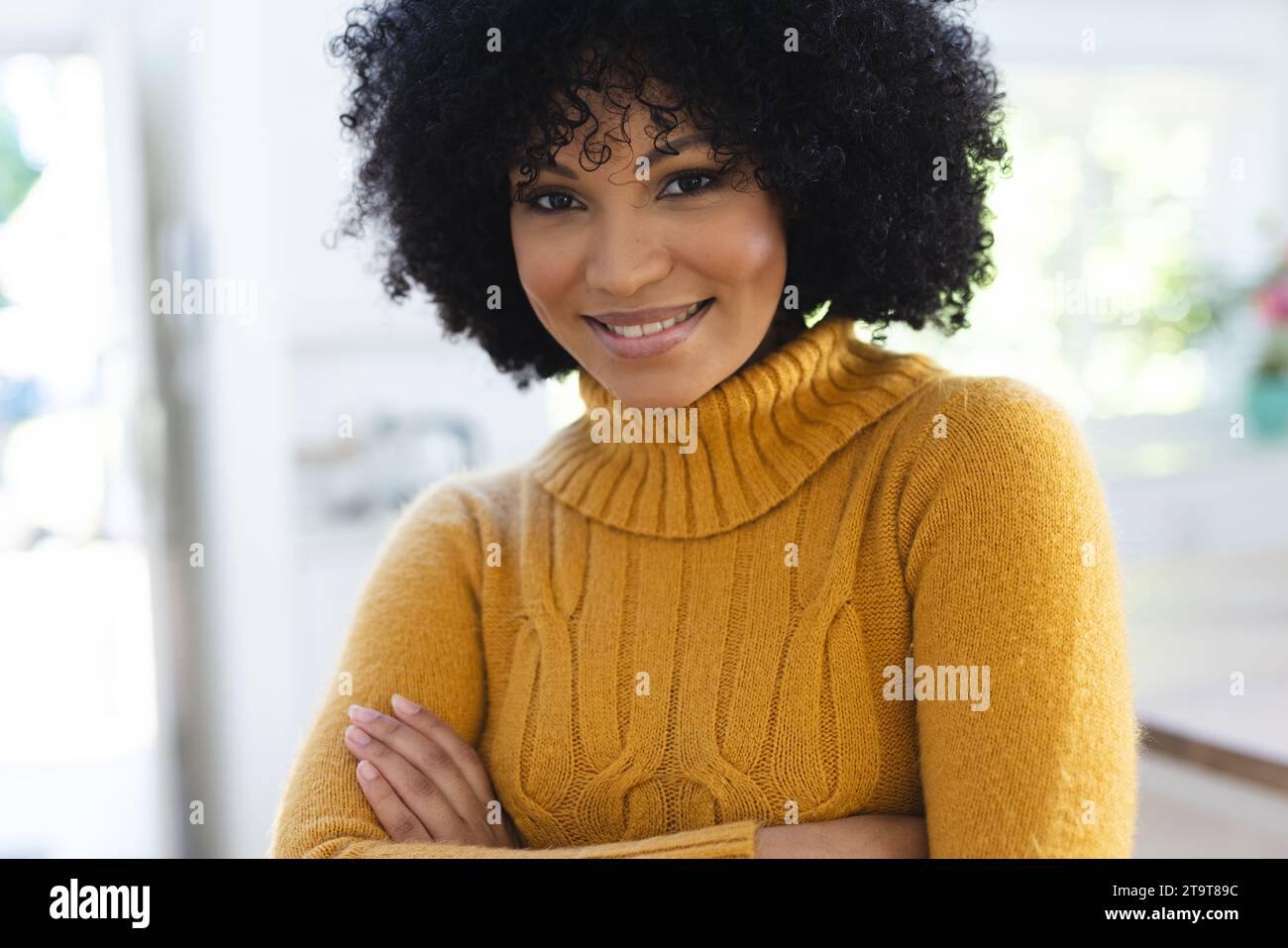 Felice donna afro-americana in piedi con le braccia incrociate a casa, spazio copia. All'interno, espressione, gesticolazione, linguaggio del corpo e femminilità, inalterati Foto Stock
