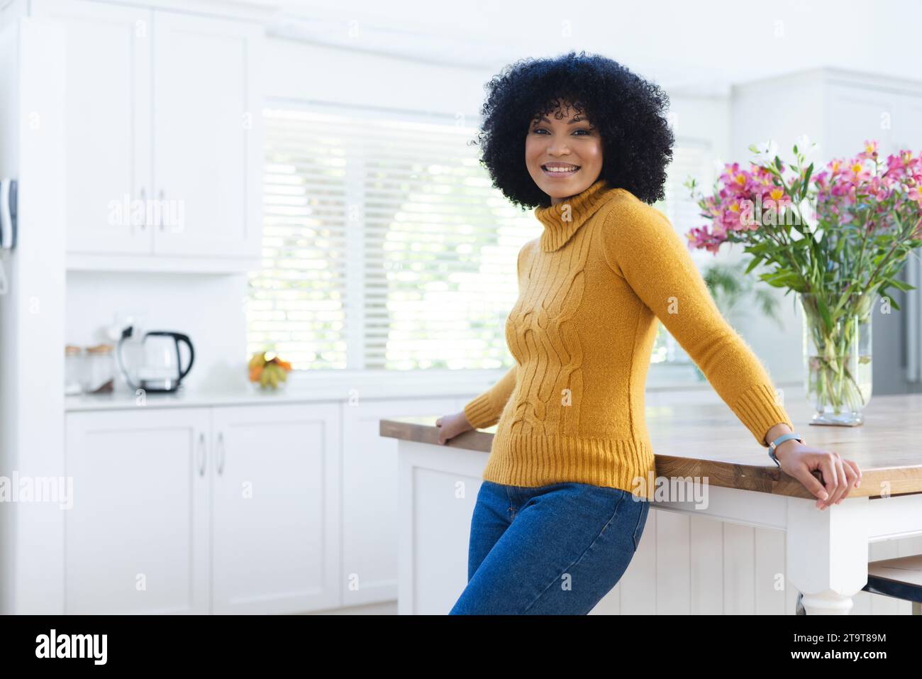 Felice donna afroamericana al bancone della cucina a casa, spazio fotocopie. All'interno, espressione, gesticolazione, linguaggio del corpo e femminilità, inalterati. Foto Stock