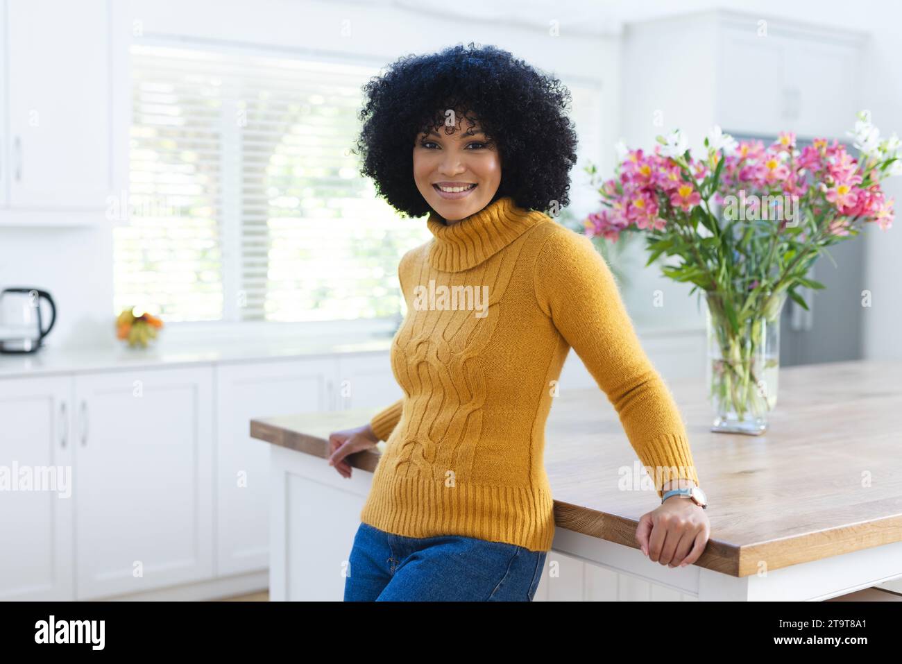Felice donna afro-americana appoggiata al bancone della cucina a casa, spazio fotocopie. All'interno, espressione, gesticolazione, linguaggio del corpo e femminilità, inalterati Foto Stock