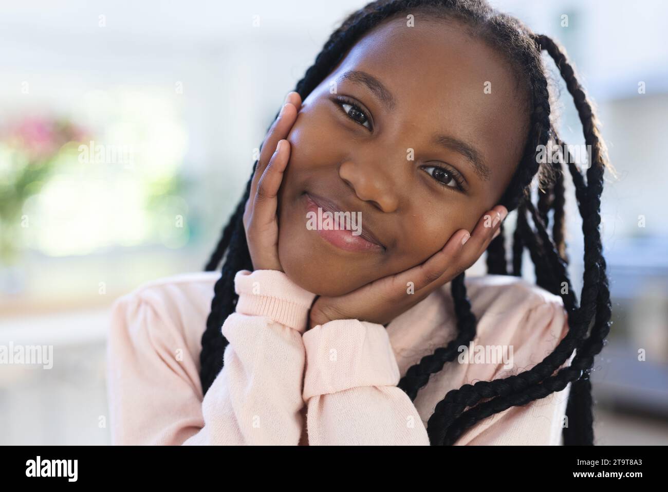 Felice ragazza afro-americana con le mani sul viso a casa, primo piano, spazio per copiare. Infanzia, espressione, gesticolazione e vita domestica, inalterati. Foto Stock