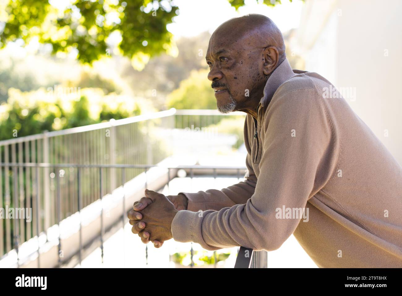 Profilo di un anziano afroamericano sulla terrazza soleggiata. Stile di vita, pensione, stile di vita anziano, natura e vita domestica, inalterati. Foto Stock