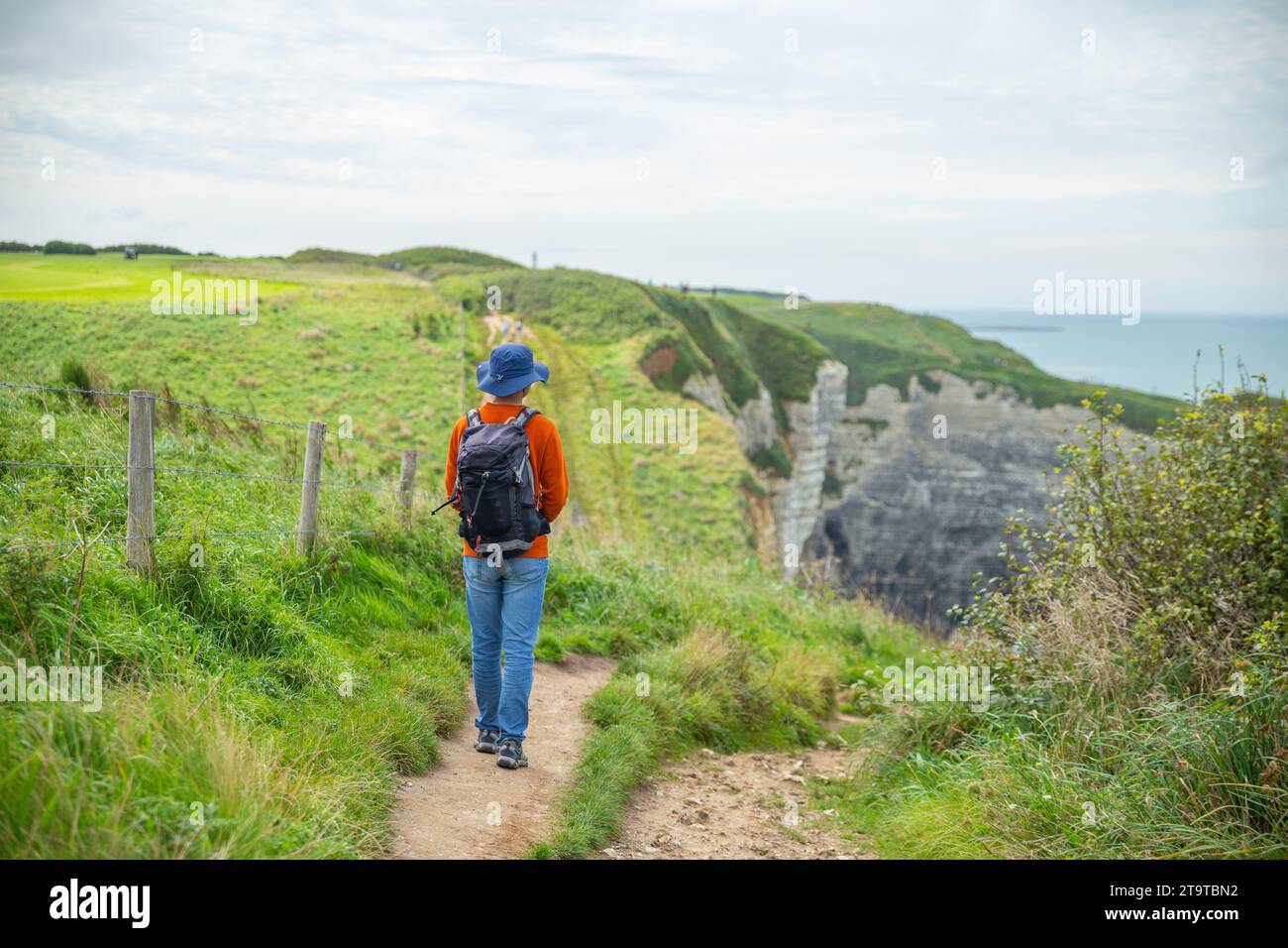 Un uomo asiatico con zaino che cammina sulla scogliera di Estretat, Francia Foto Stock
