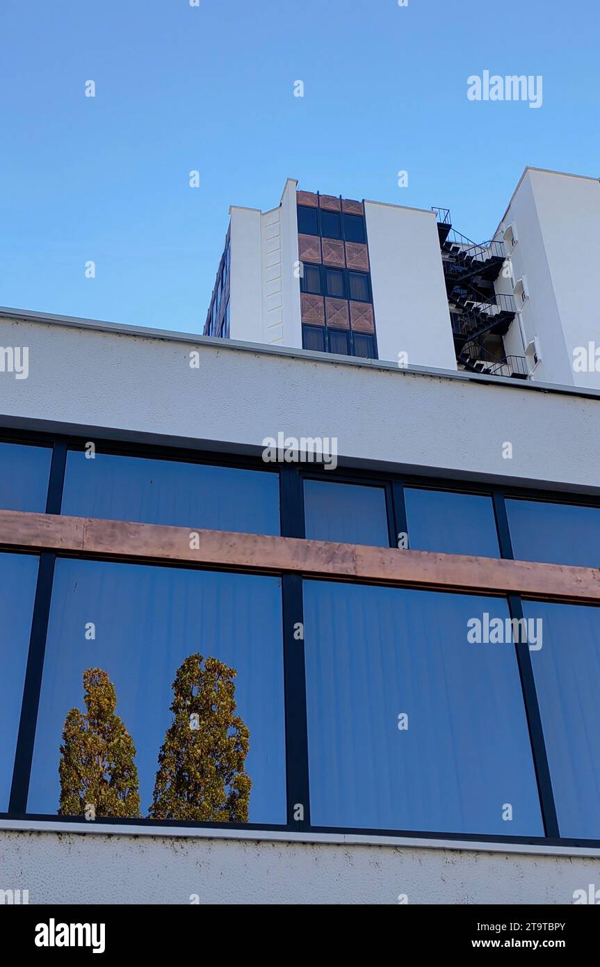 Architettura dell'edificio alberghiero. Riflesso degli alberi verdi nel vetro. Uscita di emergenza delle scale. Foto Stock