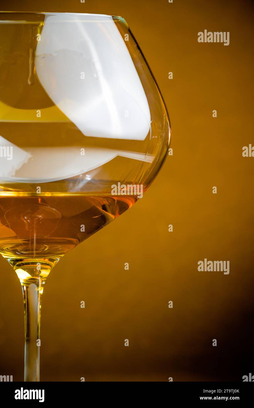 vino bianco in un bicchiere su sfondo dorato con spazio per il testo e un'atmosfera calda Foto Stock