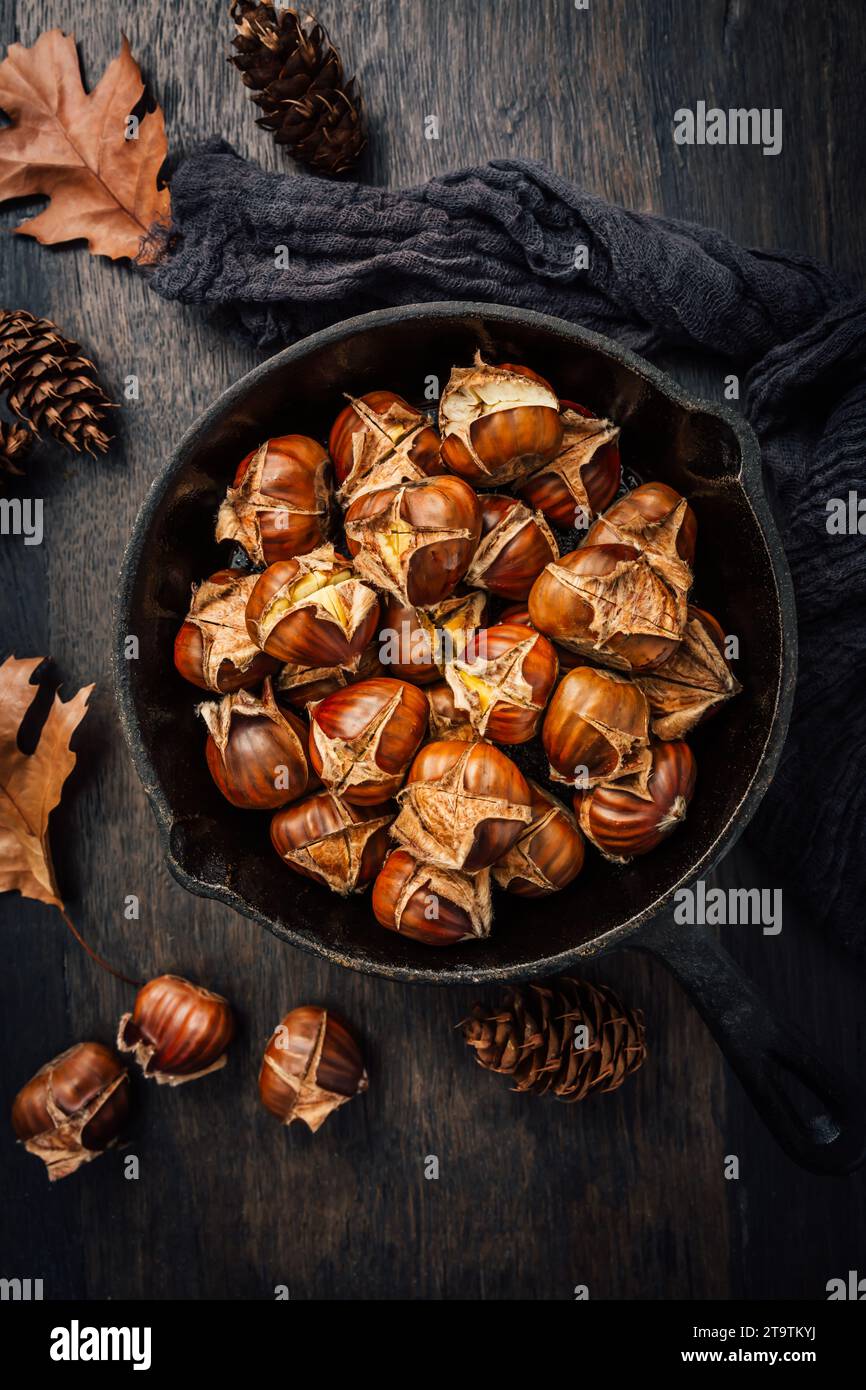 Castagne arrostite in una teglia di ferro su un vecchio tavolo da cucina Foto Stock
