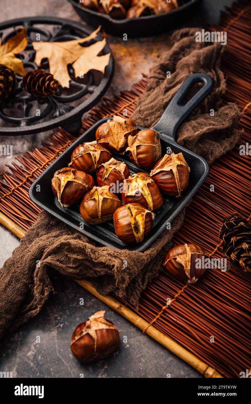 Castagne arrostite in una teglia di ferro su un vecchio tavolo da cucina Foto Stock