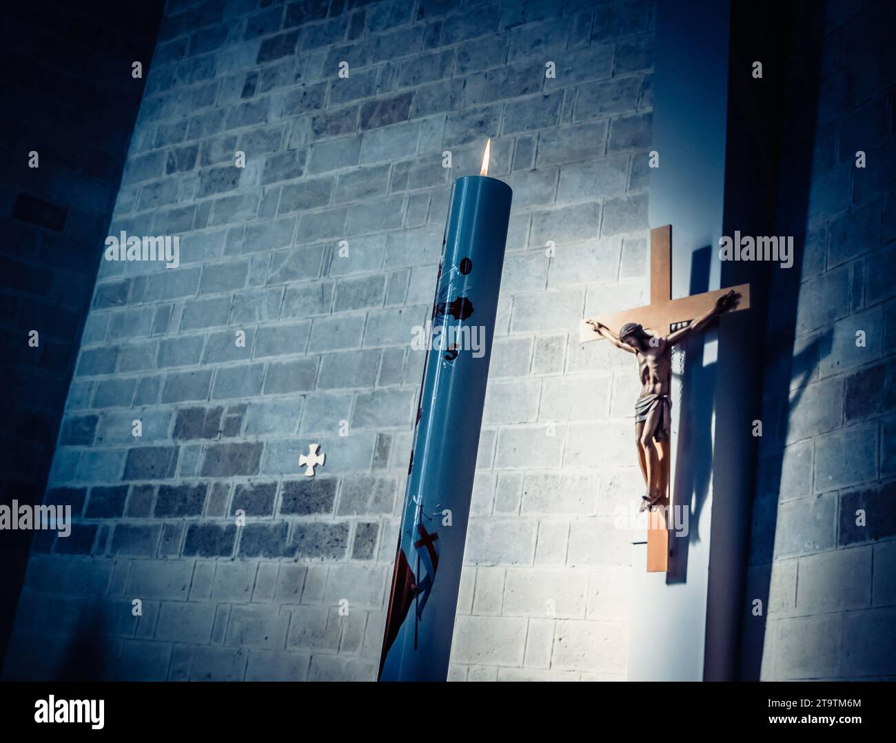 croce e candela in chiesa su sfondo blu scuro chiaro Foto Stock