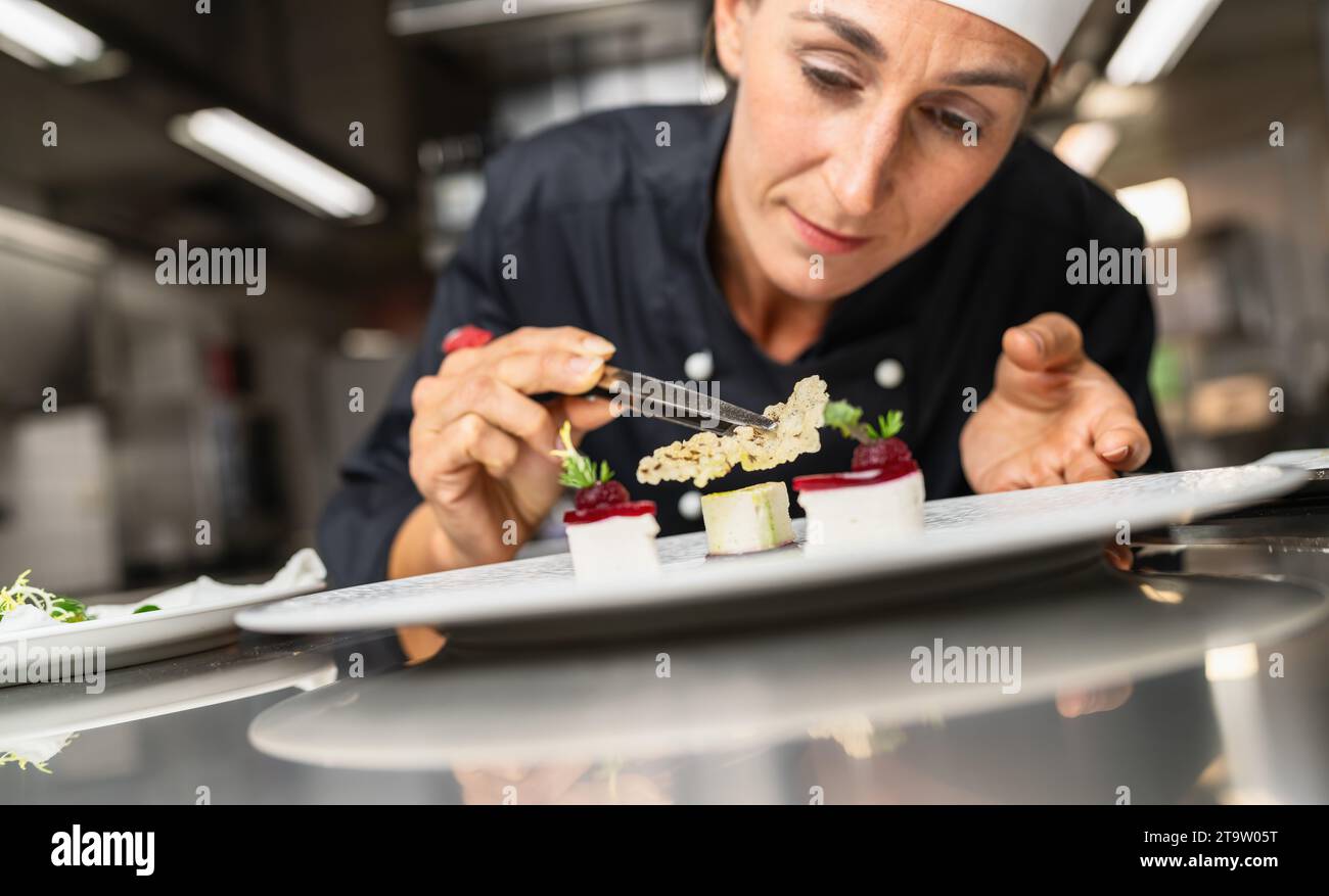 Lo chef sta perfezionando un dessert gourmet aggiungendo il condimento di riso e il piatto finale, decorando il pasto alla fine Immagine del concetto di cucina di un hotel di lusso. Foto Stock