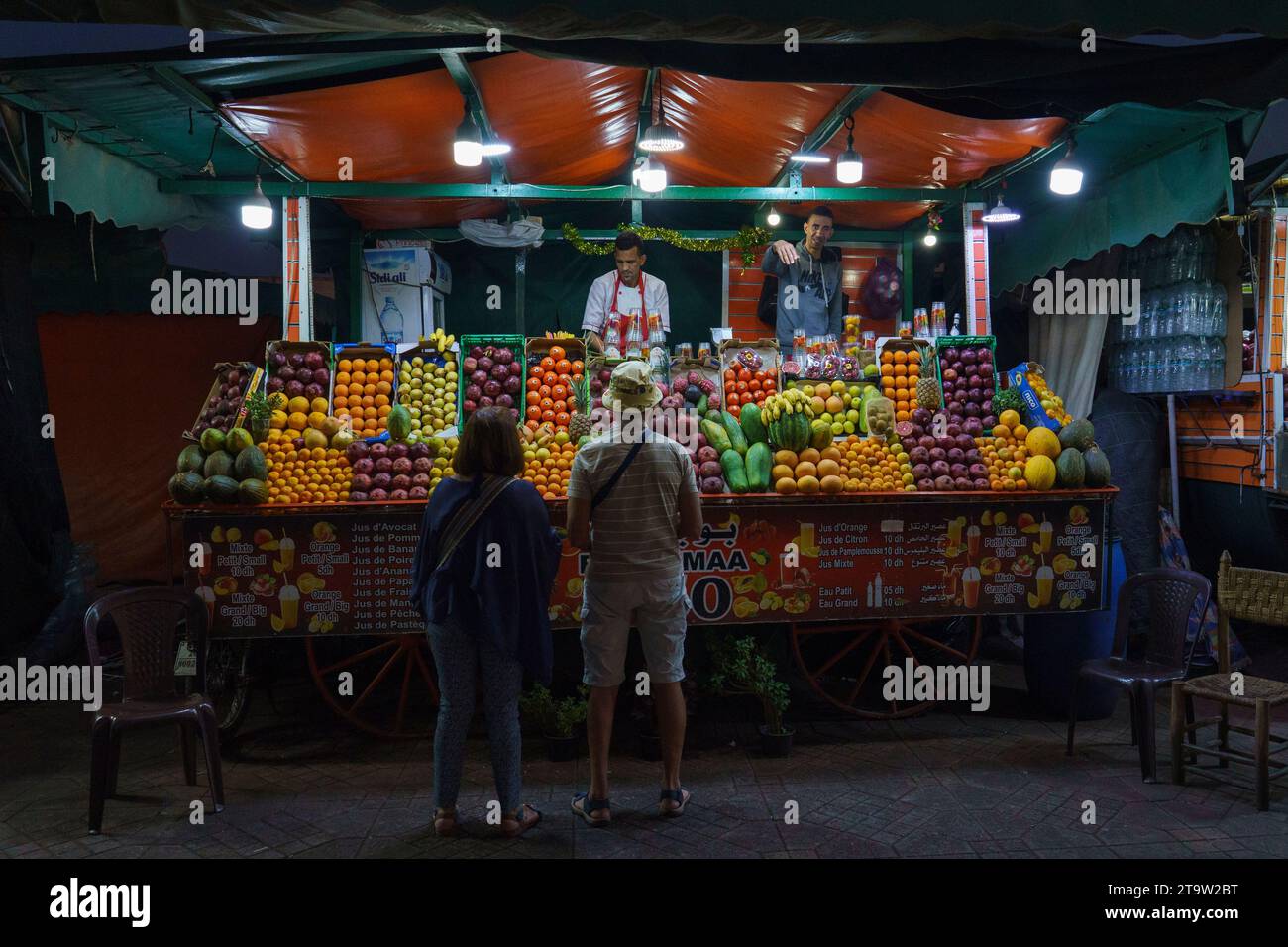 Nord Africa. Marocco. Marrakesh. Un paio di turisti di fronte a una bancarella di venditori di succhi di frutta a jemaa el fna di notte Foto Stock