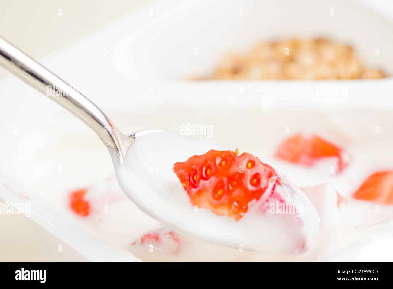 primo piano di fragola sana e yogurt bianco sul cucchiaio, concetto di nutrizione alimentare sana Foto Stock