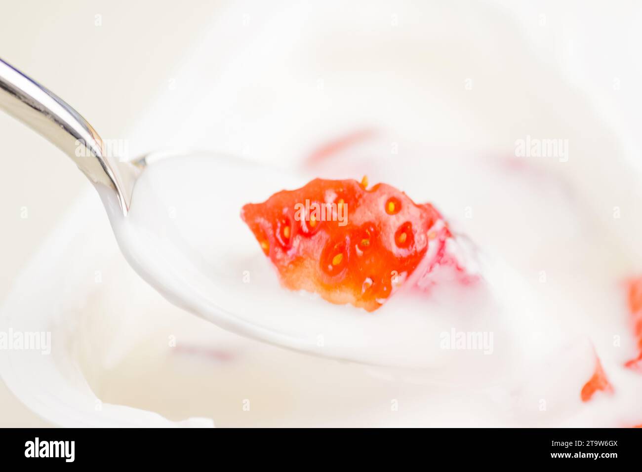 primo piano di fragola sana e yogurt bianco sul cucchiaio, concetto di nutrizione alimentare sana Foto Stock