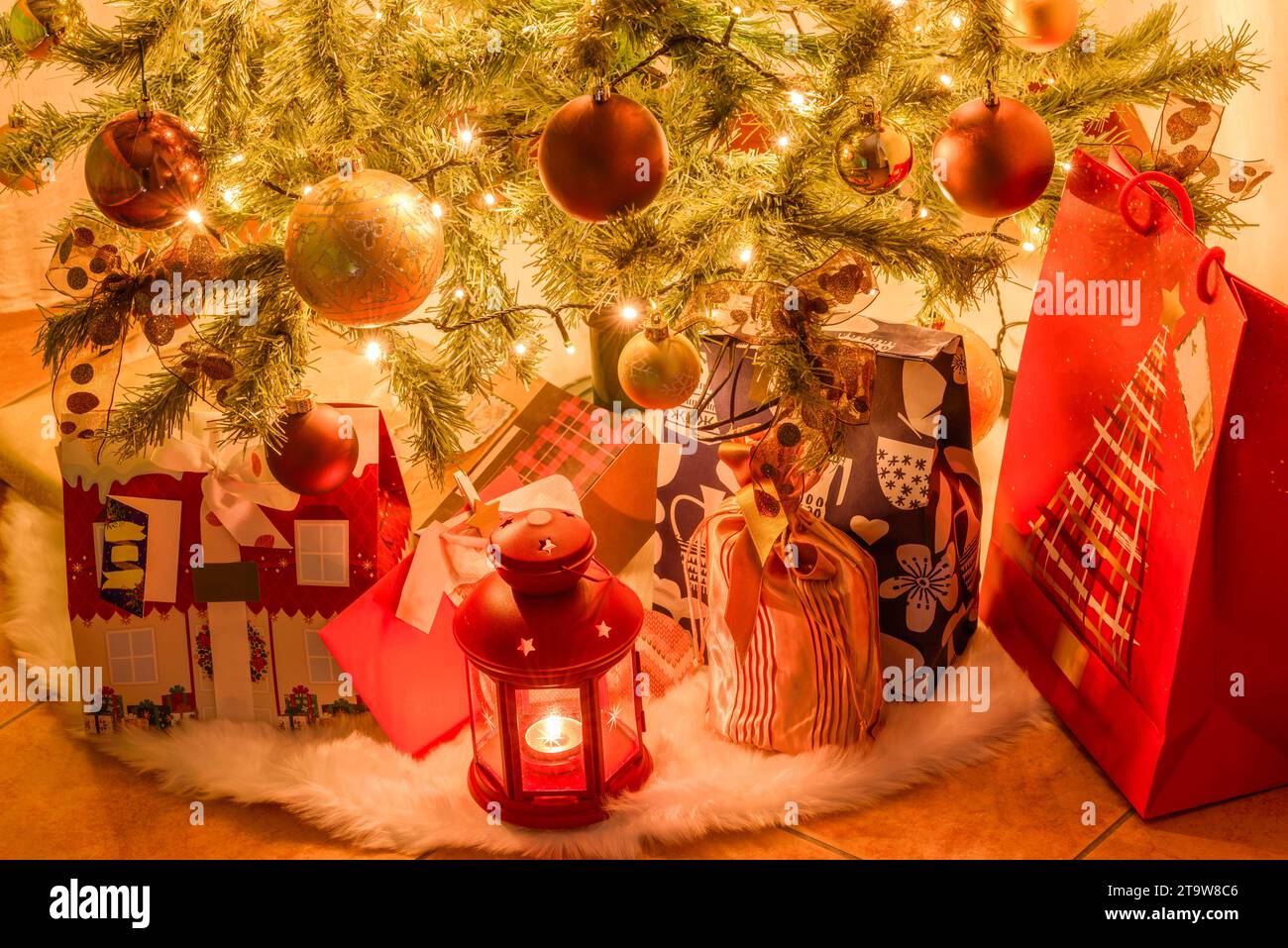 Regali di Natale e una lanterna sotto un albero di Natale inddor Foto Stock
