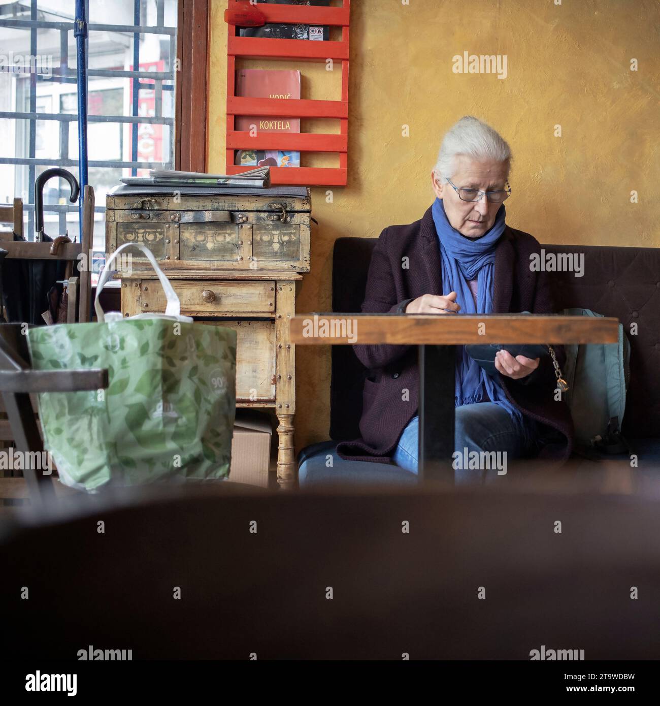Belgrado, Serbia, 19 novembre 2023: Una donna dai capelli grigi siede in un bar in attesa del suo ordine Foto Stock