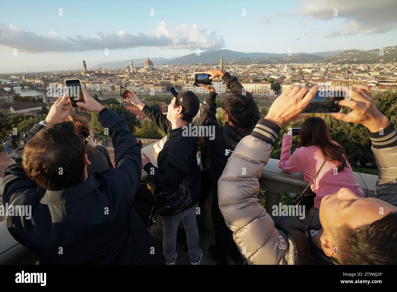 Persone, turisti e visitatori che si sono riuniti al Piazzale Michelangelo e hanno scattato una foto del panorama della città di Firenze al tramonto Foto Stock