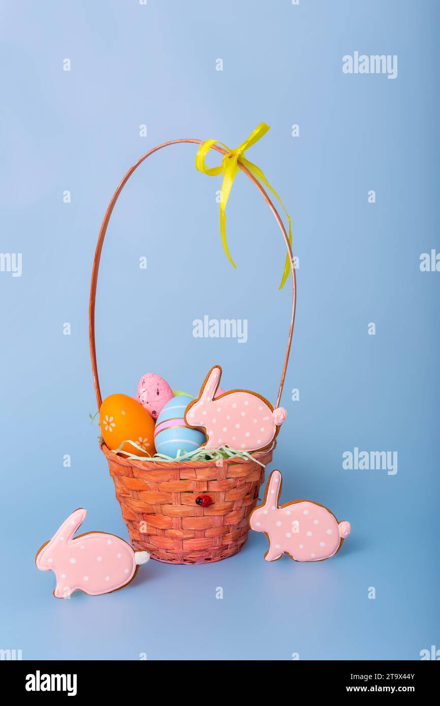 Tre pan di zenzero rosa a forma di coniglio e un cestino con uova di Pasqua decorative Foto Stock