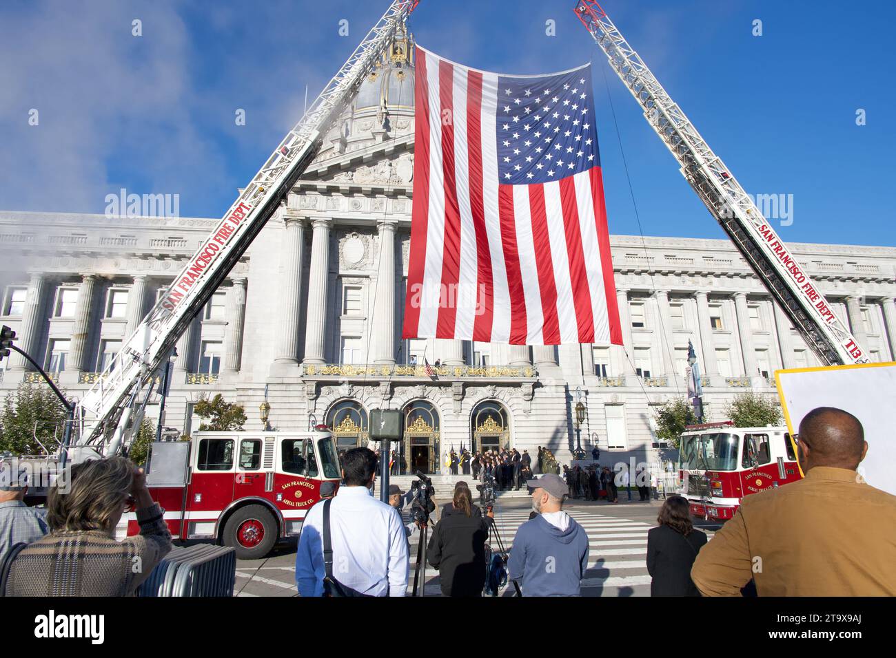 San Francisco, CA - 4 ottobre 2023: Municipio di San Francisco con la grande bandiera americana tenuta da camion dei pompieri in attesa dell'arrivo del senatore Dianne Foto Stock