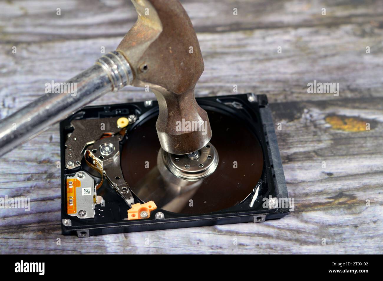 Un martello su un computer portatile memoria di archiviazione su un disco rigido da 2,5 pollici, riparare parte del computer rotta, un disco rigido aperto con piatti, mandrino, attuatore e lettura Foto Stock