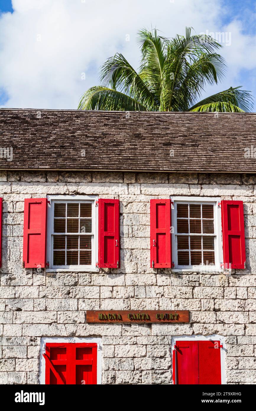 L'edificio della Magna carta Court, con persiane di colore rosso brillante, a Nassau, Bahamas, è stato costruito negli anni '1780 ed è un esempio di edificio in pietra a vista. Foto Stock