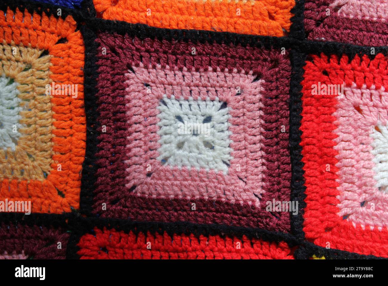 Primo piano di una coperta di lana marrone, arancione e rossa a uncinetto Foto Stock