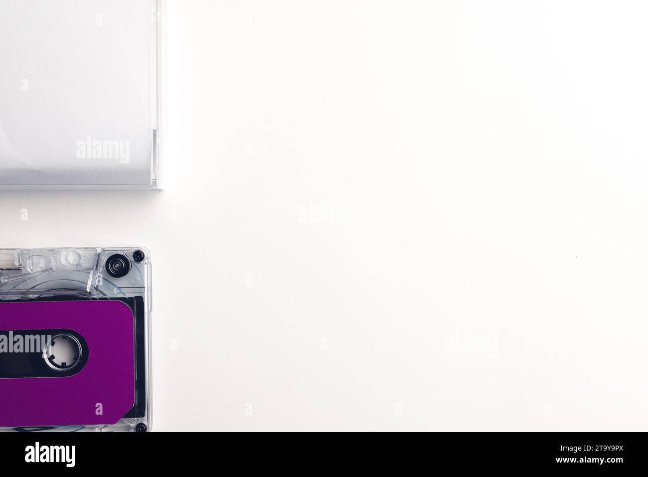 Vista dall'alto del nastro a cassetta viola e della scatola bianca con spazio per le copie disposto su sfondo bianco Foto Stock