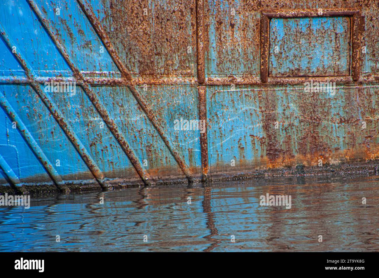 Struttura arrugginita su uno scafo blu abbandonato in un porto Foto Stock