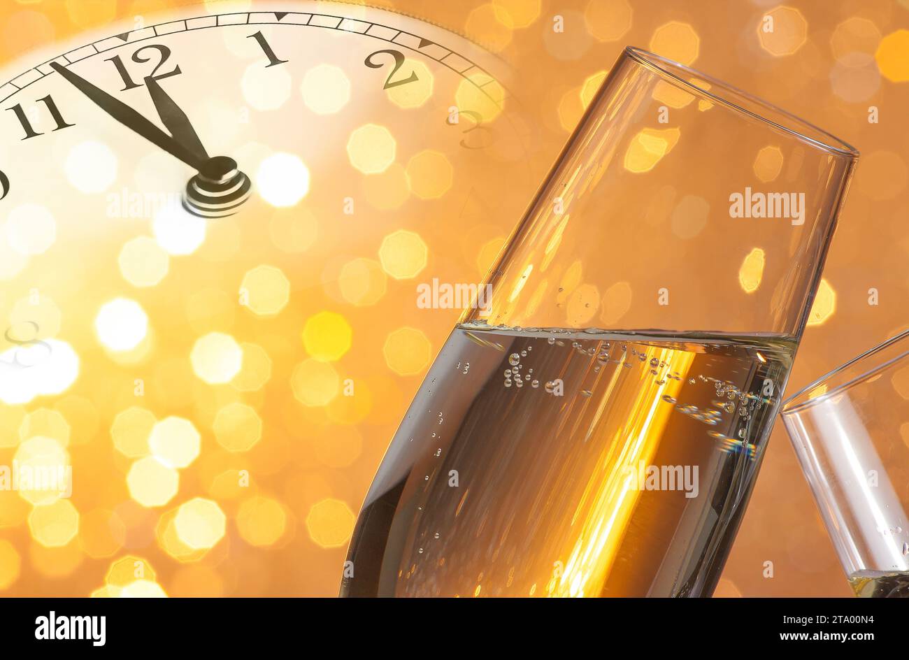 flauti di champagne con bollicine dorate fanno il tifo su sfondo bokeh chiaro dorato con la sveglia vintage che mostra il concetto di mezzanotte, felice anno nuovo Foto Stock