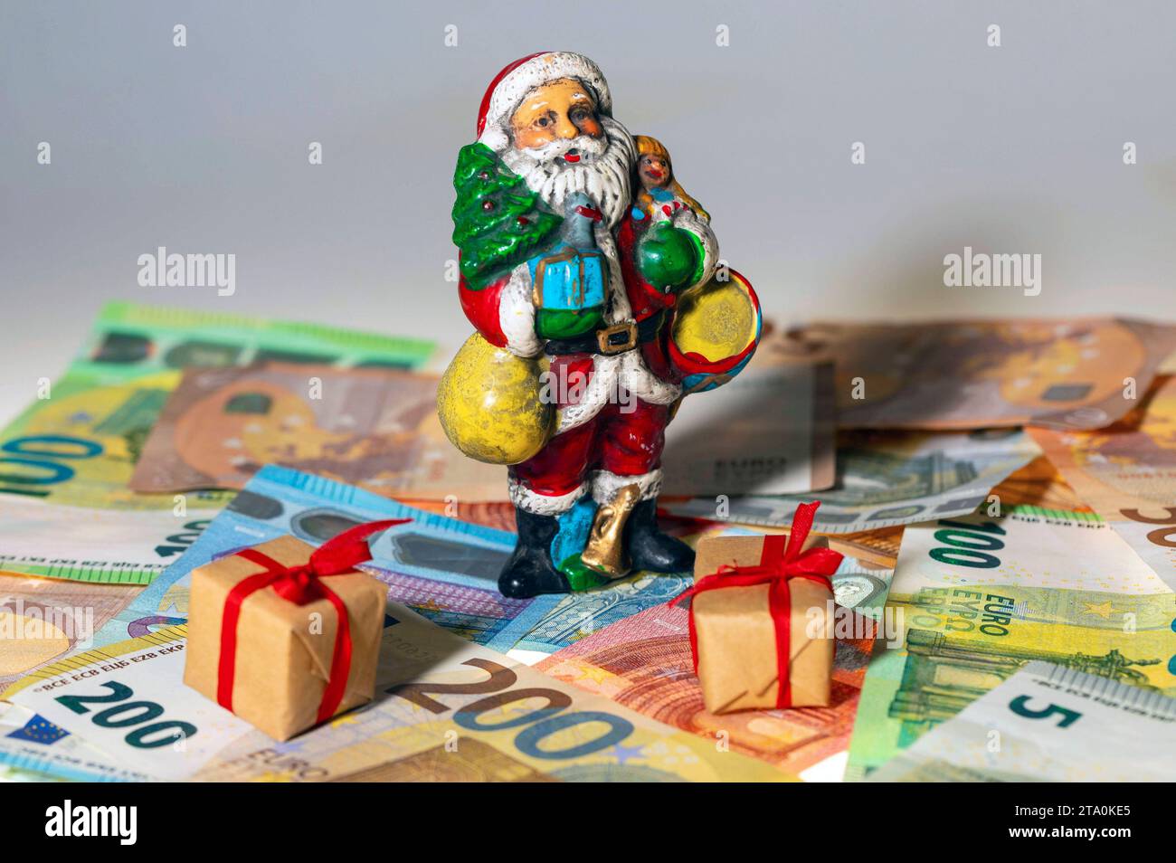 Eine Weihnachtsmann-Figur mit Geschenken steht auf Euro-Banknoten. - Weihnachtsgeld ist ein zusätzliches Entgelt des Arbeitgebers an Seine Arbeitnehmer. Die Höhe des Weihnachtsgeldes, der Zahlungszeitpunkt sowie der Umstand, ob überhaupt Weihnachtsgeld gezahlt wird, sind gesetzlich nicht geregelt. Die Zahlung soll zu den anlässlich des Weihnachtsfestes zusätzlich entstehenden Aufwendungen beitragen. Sybolfoto, Symbolbild **** Una cifra di Babbo Natale con regali è un pagamento aggiuntivo da parte del datore di lavoro ai suoi dipendenti per l'importo del bonus di Natale, th Foto Stock