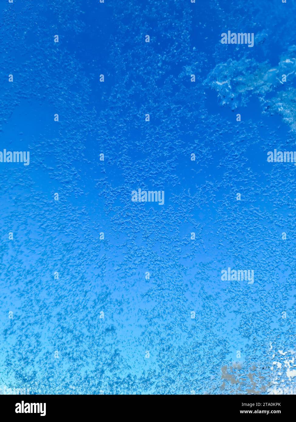Ghiaccio congelato su una finestra con sfondo blu Foto Stock