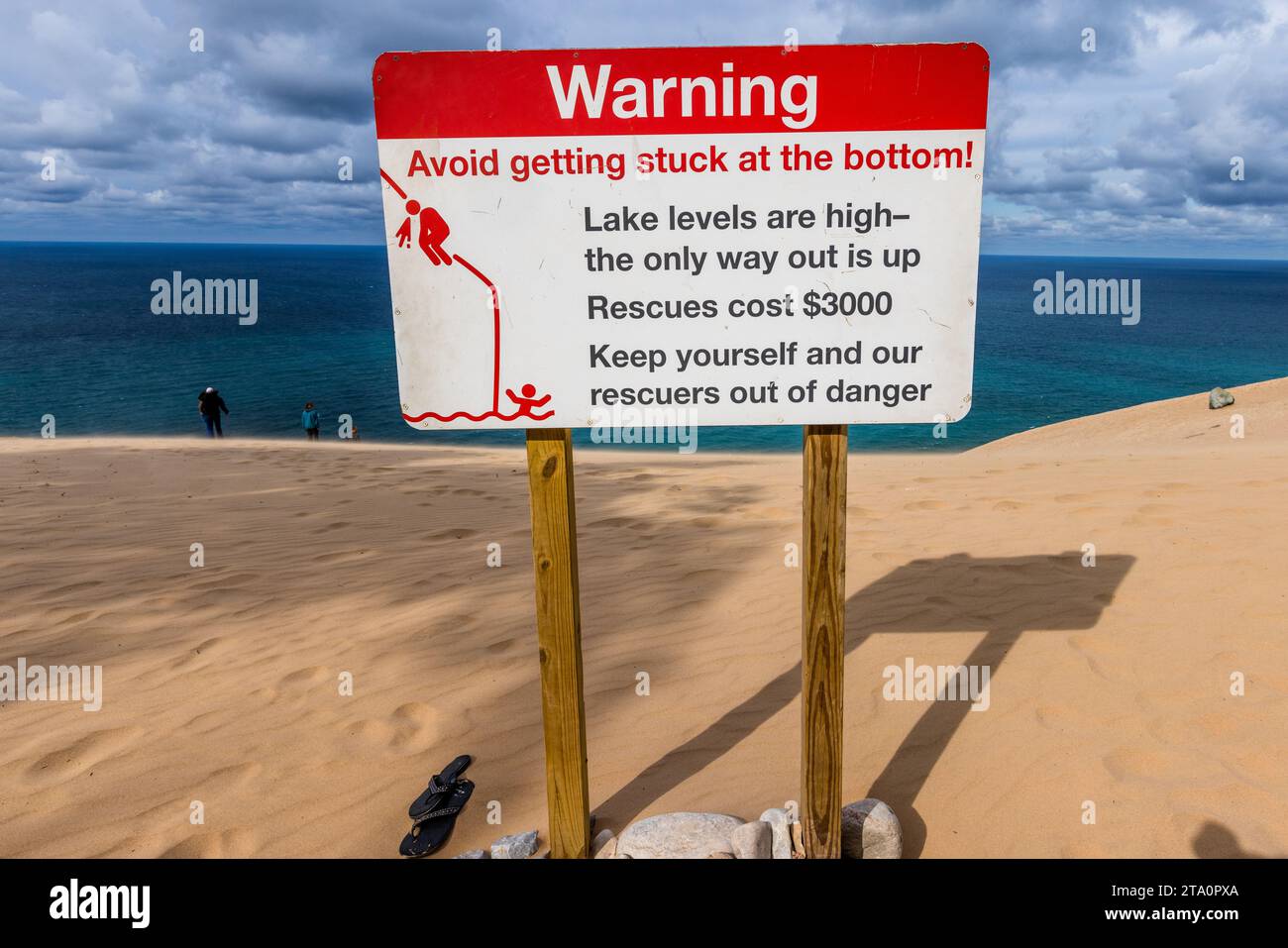 Un cartello di avvertimento su una duna al Sleeping Bear Dunes National Lakeshore vicino a Empire Township, Michigan, Stati Uniti, consiglia ai visitatori di evitare di rimanere bloccati in basso: con i livelli del lago alti, l'unica via d'uscita è verso l'alto, e un salvataggio costa 3.000 dollari. Foto Stock