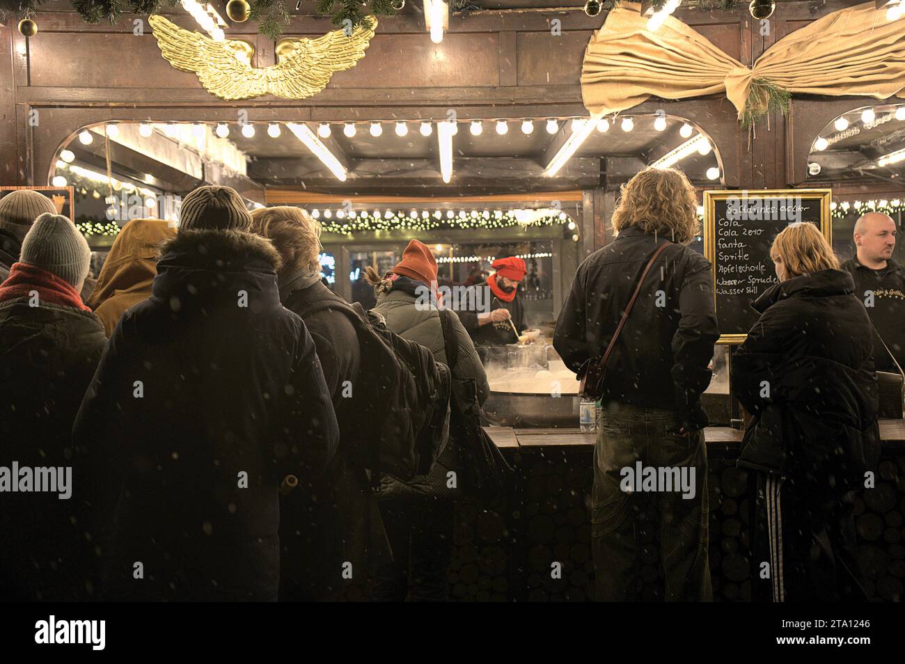 La gente si mette in fila per comprare cibo al mercatino di Natale del castello di Charlottenburg, mentre nevica Berlino, in Germania Foto Stock