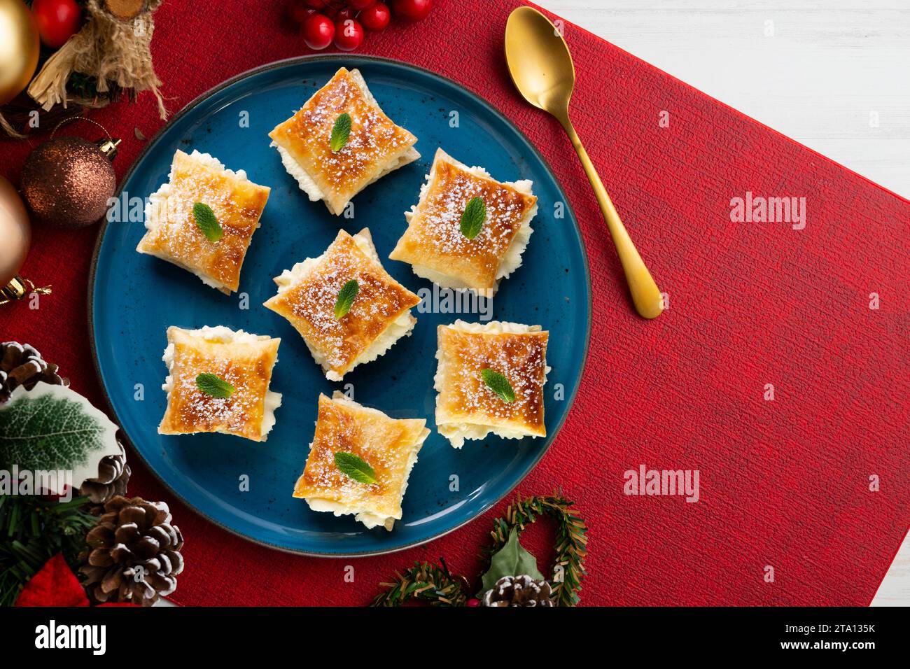 Miguelitos de la Rueda. Dessert spagnolo tradizionale con pasta sfoglia e ripieno di panna. Cibo natalizio servito su un tavolo decorato con Natale Foto Stock