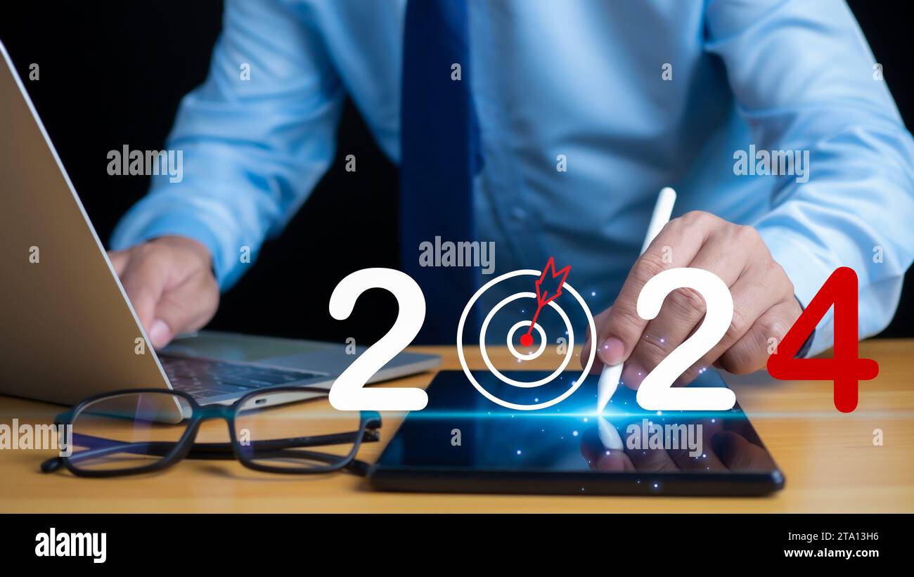 Negoziazione di azioni. Finanza. Investimenti. Business in crescita. Uomo d'affari in completo che punta con la penna sullo schermo del tablet e scrive 2024 che mostra il concetto di set Foto Stock