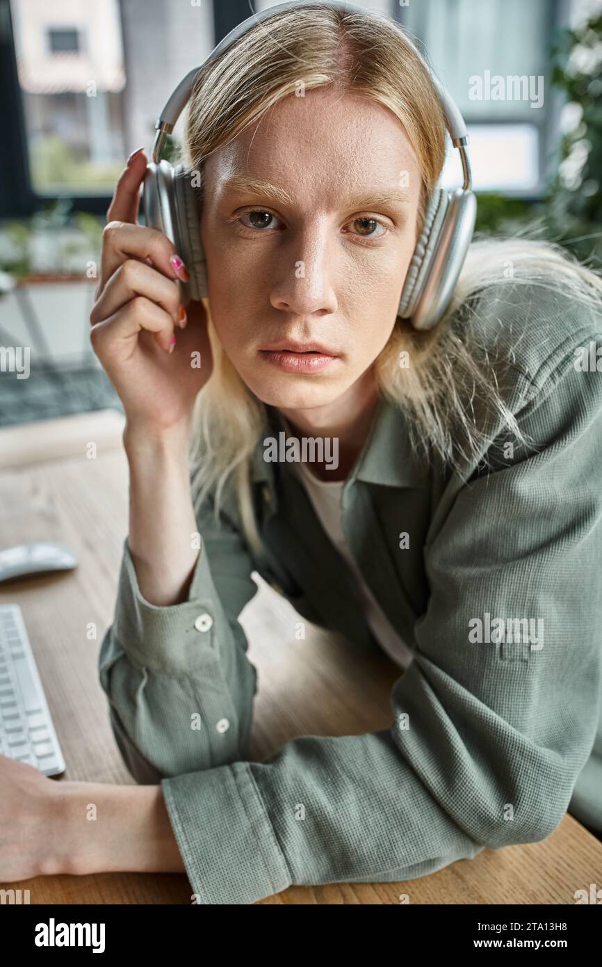 ritratto di una giovane persona androgina in abbigliamento casual con cuffie che guardano la fotocamera, il lavoro Foto Stock