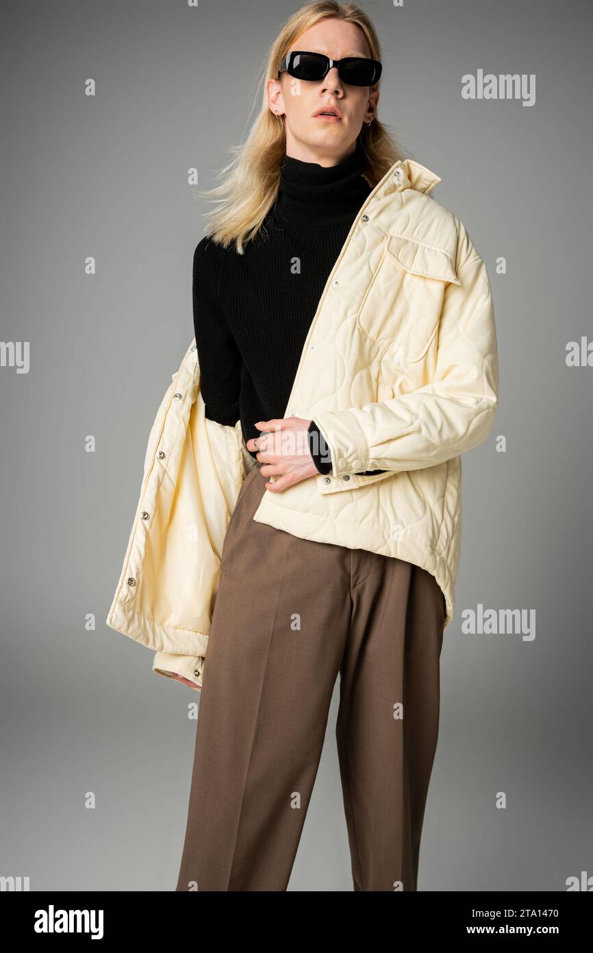 scatto verticale di una persona androgina dall'aspetto elegante in un abbigliamento elegante che guarda la fotocamera e la moda Foto Stock