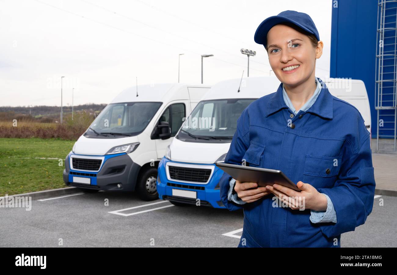 Responsabile donna con un tablet digitale sullo sfondo dei furgoni. Gestione della flotta Foto Stock