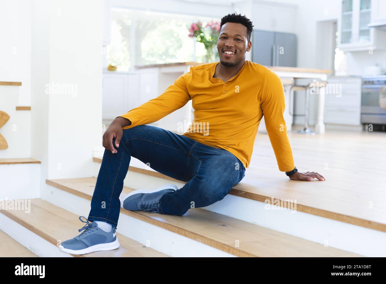 Felice afro-americano seduto sulle scale a casa, spazio fotocopie. Espressione, gesticolazione e vita domestica, inalterata. Foto Stock