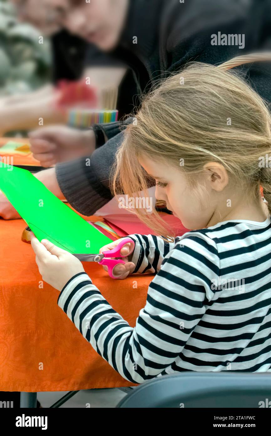 un bambino taglia le statuette dalla carta colorata. Foto Stock