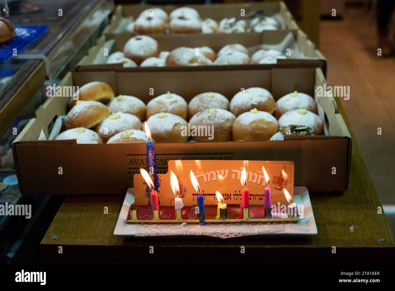Una menorah Hanukkah brucia in una panetteria di Gerusalemme che vende ciambelle ricoperte di zucchero durante la celebrazione dell'Hanukkah, il Festival delle luci in Israele. Foto Stock