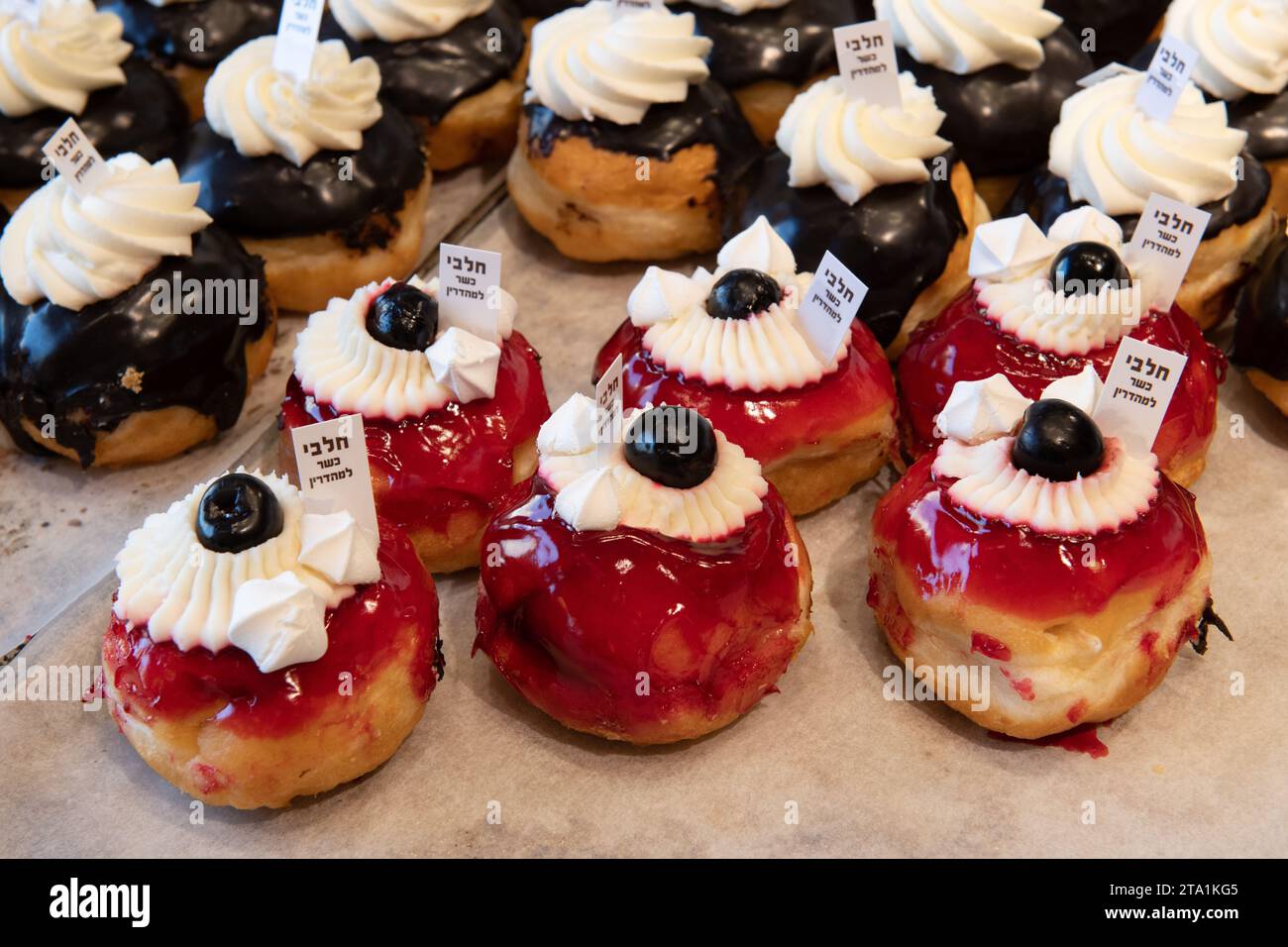 Ciambelle decorative in una panetteria di Gerusalemme durante la celebrazione della festa ebraica di Hanukkah, quando è tradizionale mangiare cibi fritti in olio. Foto Stock
