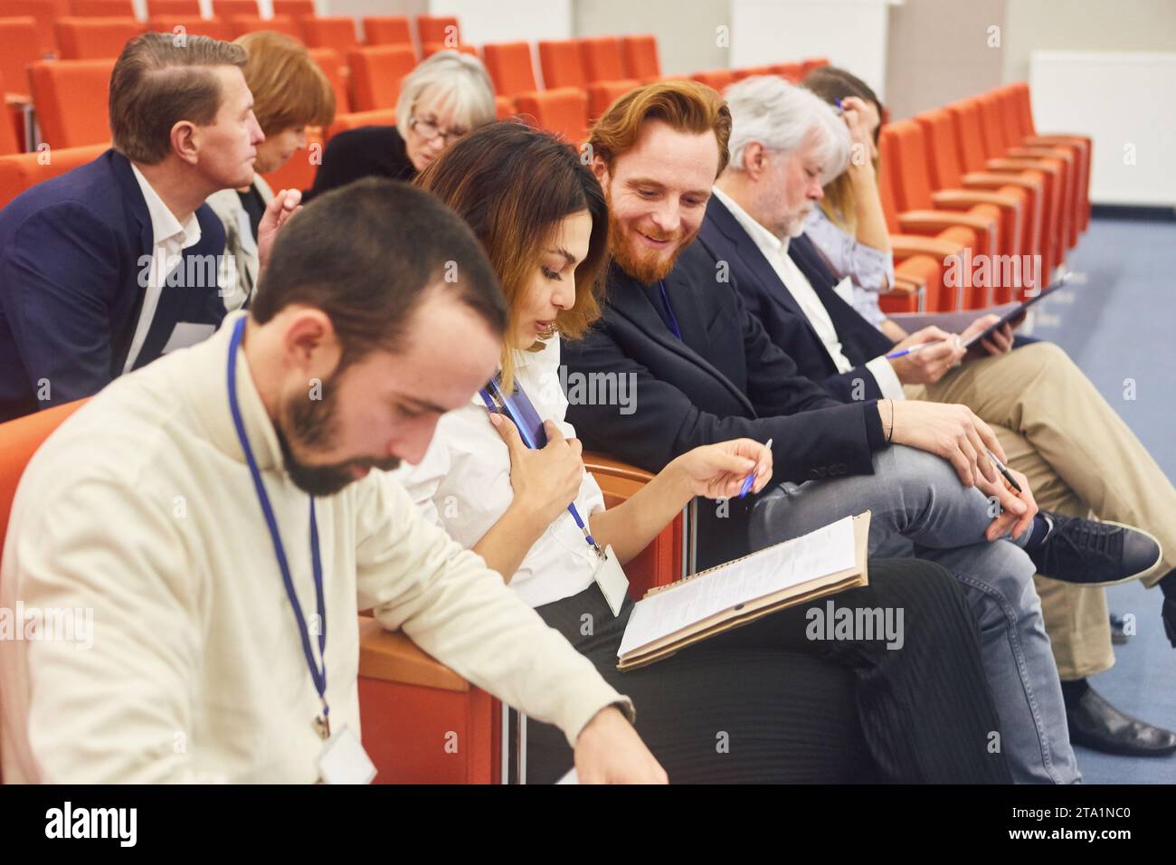 Professionisti maschili e femminili che discutono mentre sono seduti in pubblico a una conferenza aziendale Foto Stock