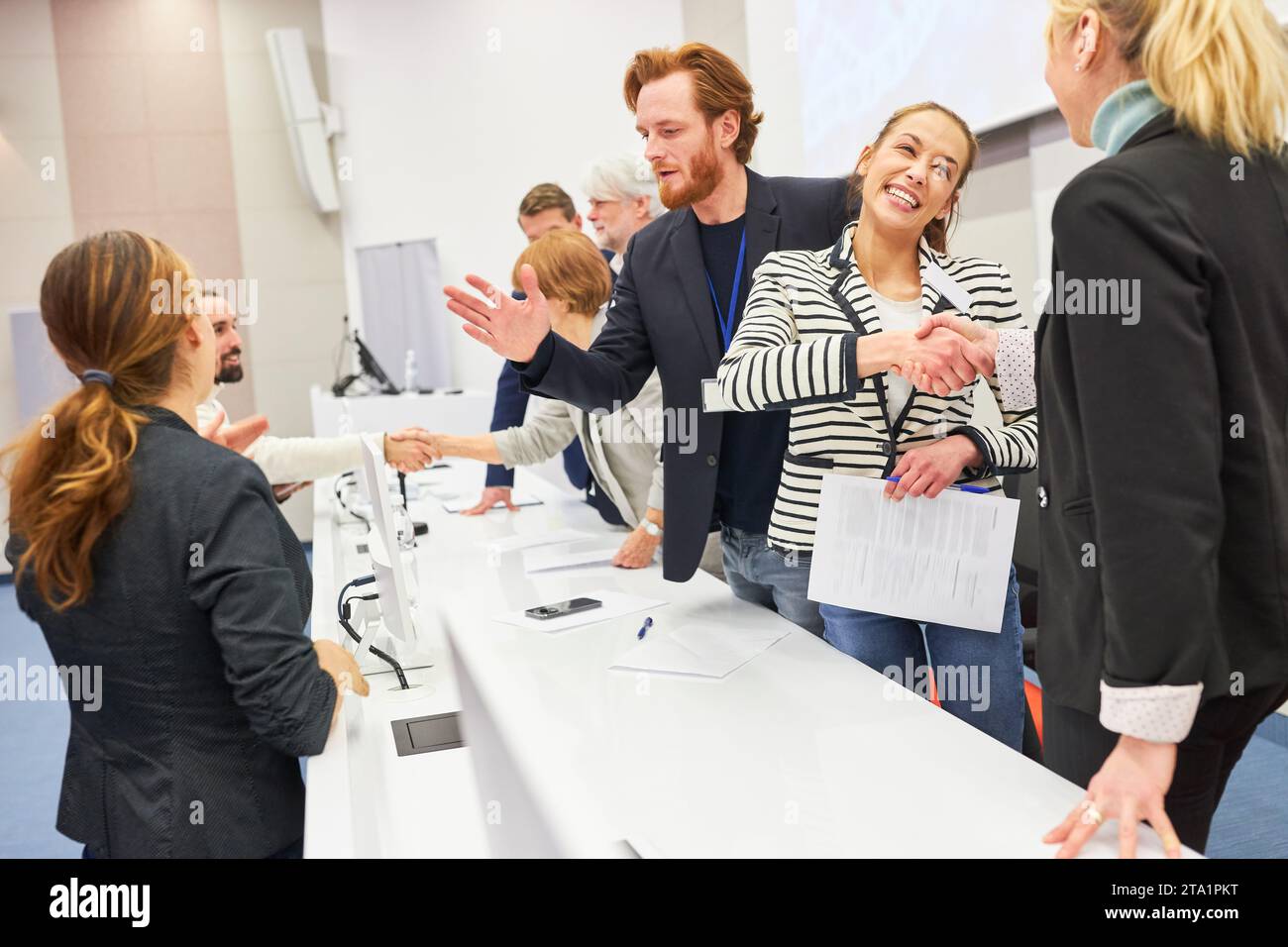 Felice donna d'affari che stringe le mani con un collega sul palco durante un evento d'affari nell'auditorium Foto Stock