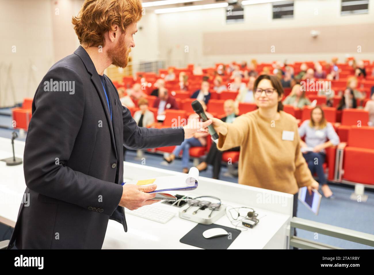 Oratore maschile che fornisce il microfono al pubblico durante le conferenze aziendali nell'auditorium Foto Stock