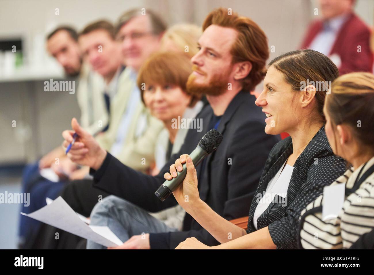 Donna d'affari che risponde tramite microfono durante un seminario d'affari al centro convegni Foto Stock