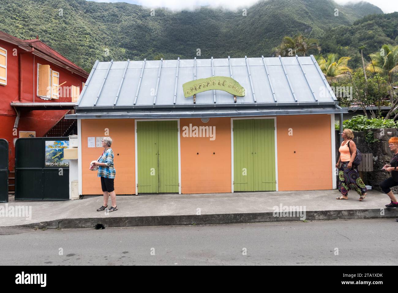 Creperie le Gall nel villaggio di Hell-Bourg, Reunion Island, Francia. Porte verdi con facciata arancione. Foto Stock