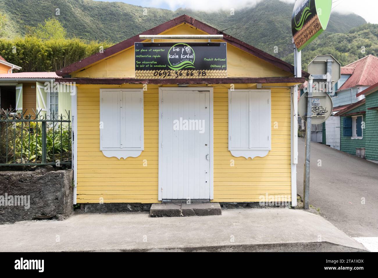 Le Petit Coin Kréol, negozio di artigianato con pareti gialle nel villaggio di Hell-Bourg, Reunion Island, Francia. Porte verdi con facciata arancione. Foto Stock