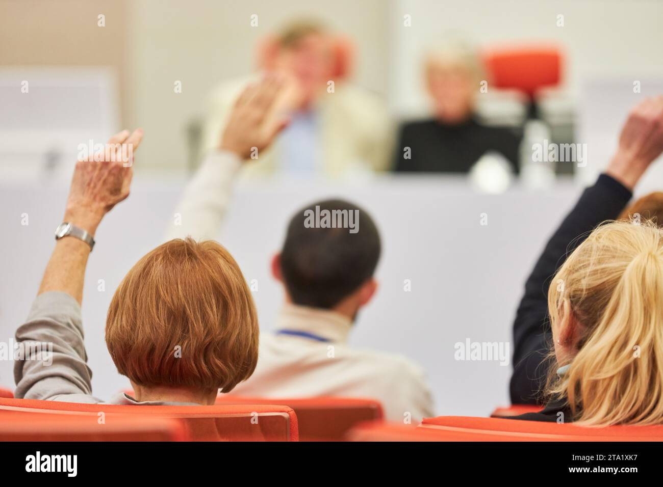 Donna seduta al pubblico che fa domande durante una conferenza aziendale nell'auditorium Foto Stock