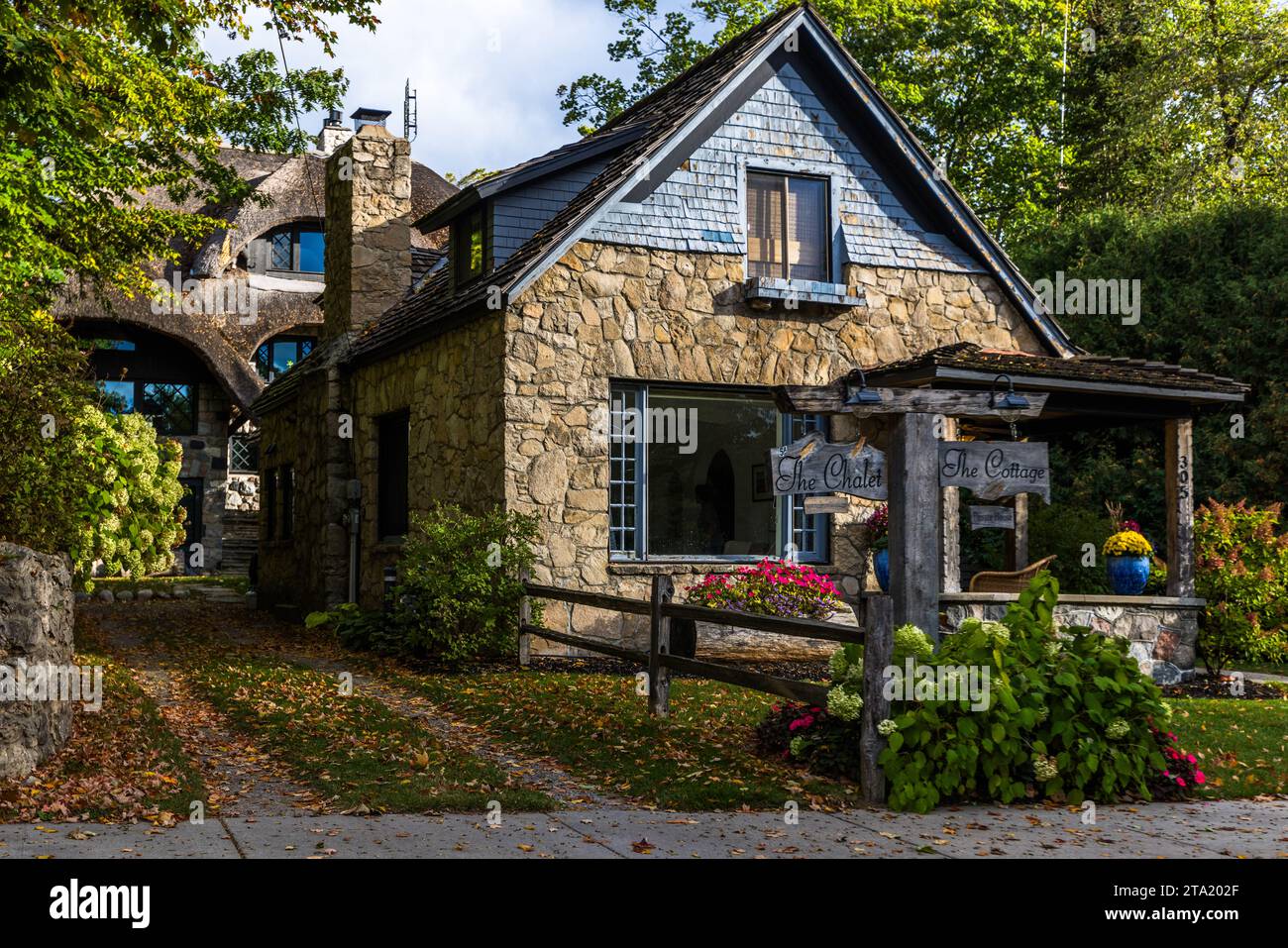 La più piccola delle case a forma di fungo di Earl A. Young a Charlevoix porta i cartelli "Il Chalet" e "Il Cottage" all'ingresso, con una casa in pietra più grande e il suo tetto curvo che si erge sullo sfondo. In oltre 52 anni, l'architetto autodidatta ha progettato e costruito 31 edifici a Charlevoix, 28 case e tre strutture commerciali. Charlevoix, Michigan, Stati Uniti. Foto Stock