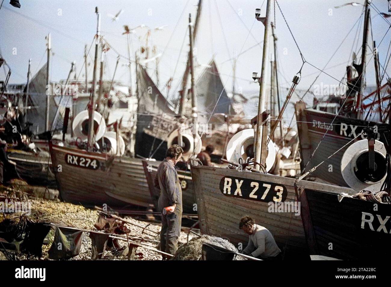 Foto colorata in BW delle imbarcazioni del mercato del pesce di Hastings nel 1980 utilizzando un teleobiettivo per comprimere la prospettiva. Si possono vedere RX273, RX274, RX60, RX90 e St Richard. Foto Stock